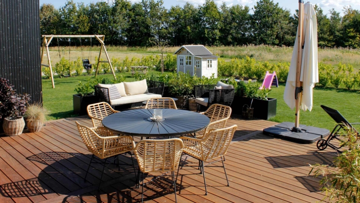 En træterrasse binder udendørsarealet sammen med huset og skaber et hyggeligt uderum med plads til livet.  
<br>.